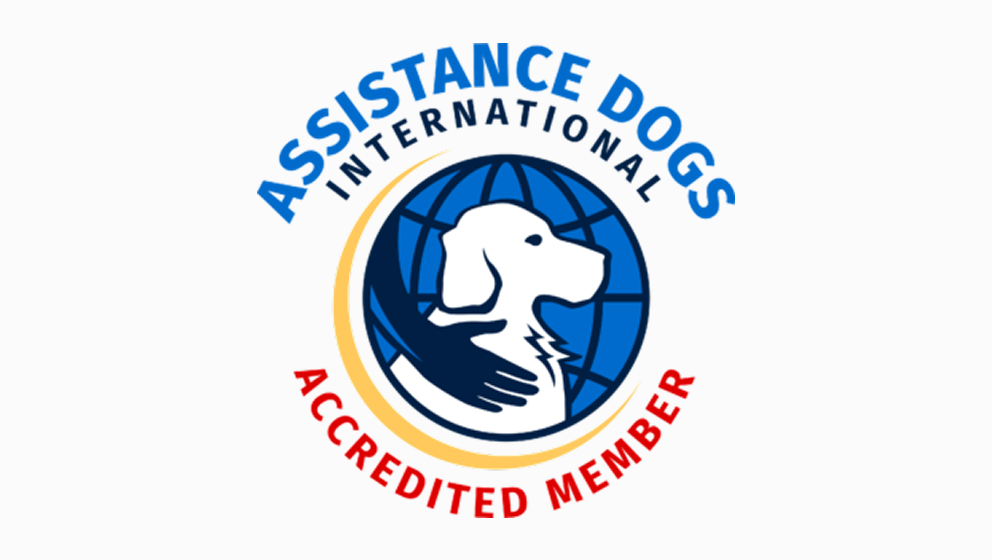 The official circular logo for Assistance Dogs International (ADI) Accredited Member, featuring a white dog silhouette outlined by a supportive hand against a blue globe graphic.