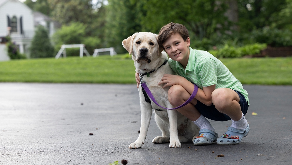 CHAMP Assistance Dogs companion dog with his young handler in a home outdoor setting.