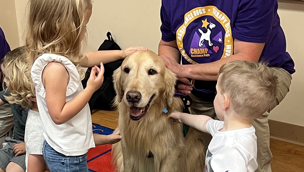 CHAMP Assistance Dogs therapy dog visiting with children at a school classroom event.